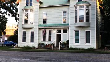A two-story house with a green roof, multiple windows, and a front porch.