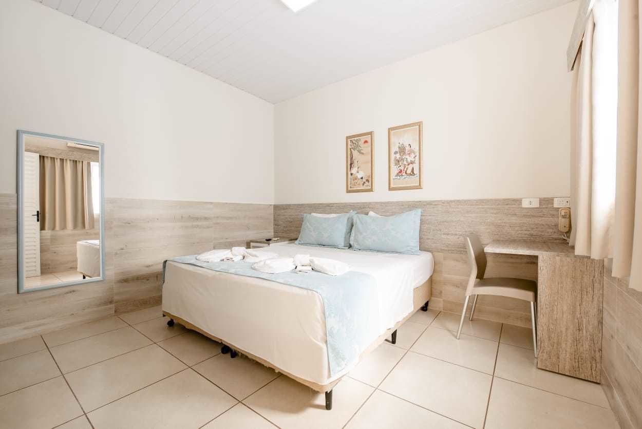 Quarto com cama, escrivaninha e cadeira.