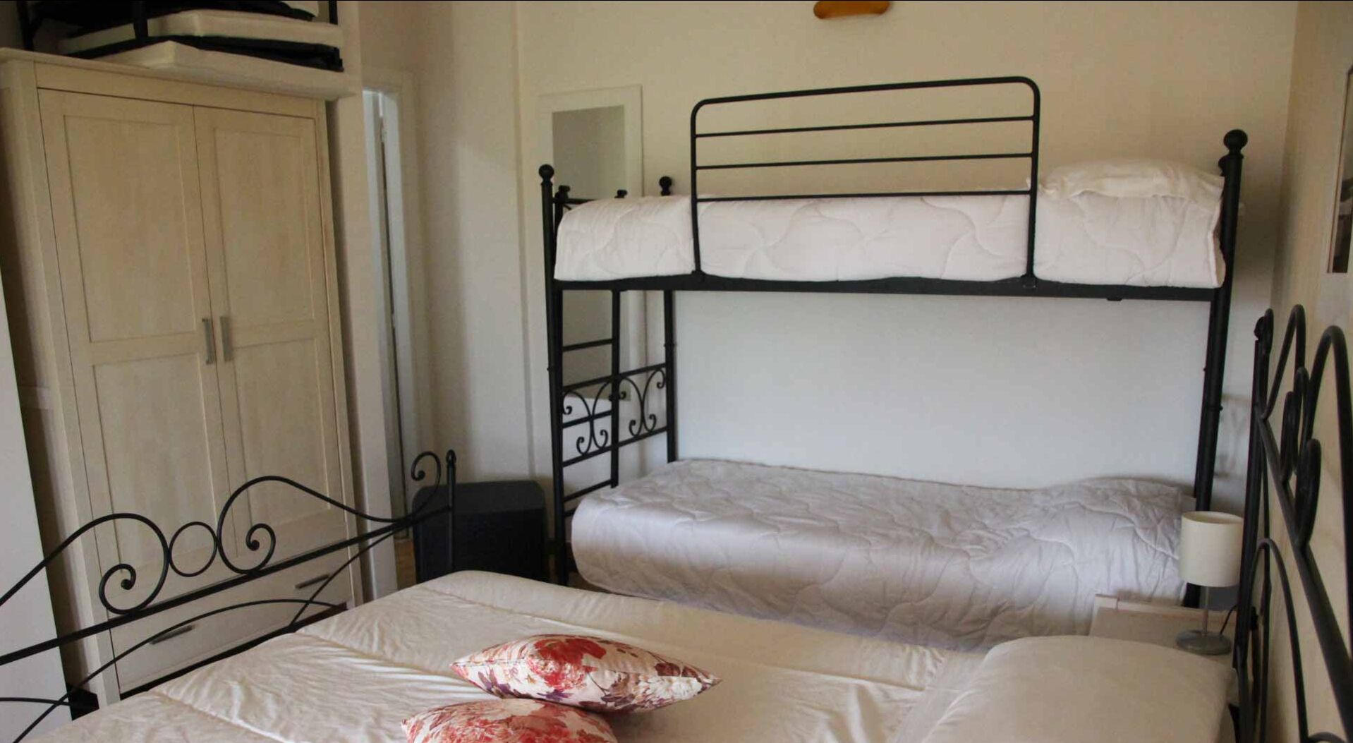 A bunk bed room with a wardrobe and a bedside table.