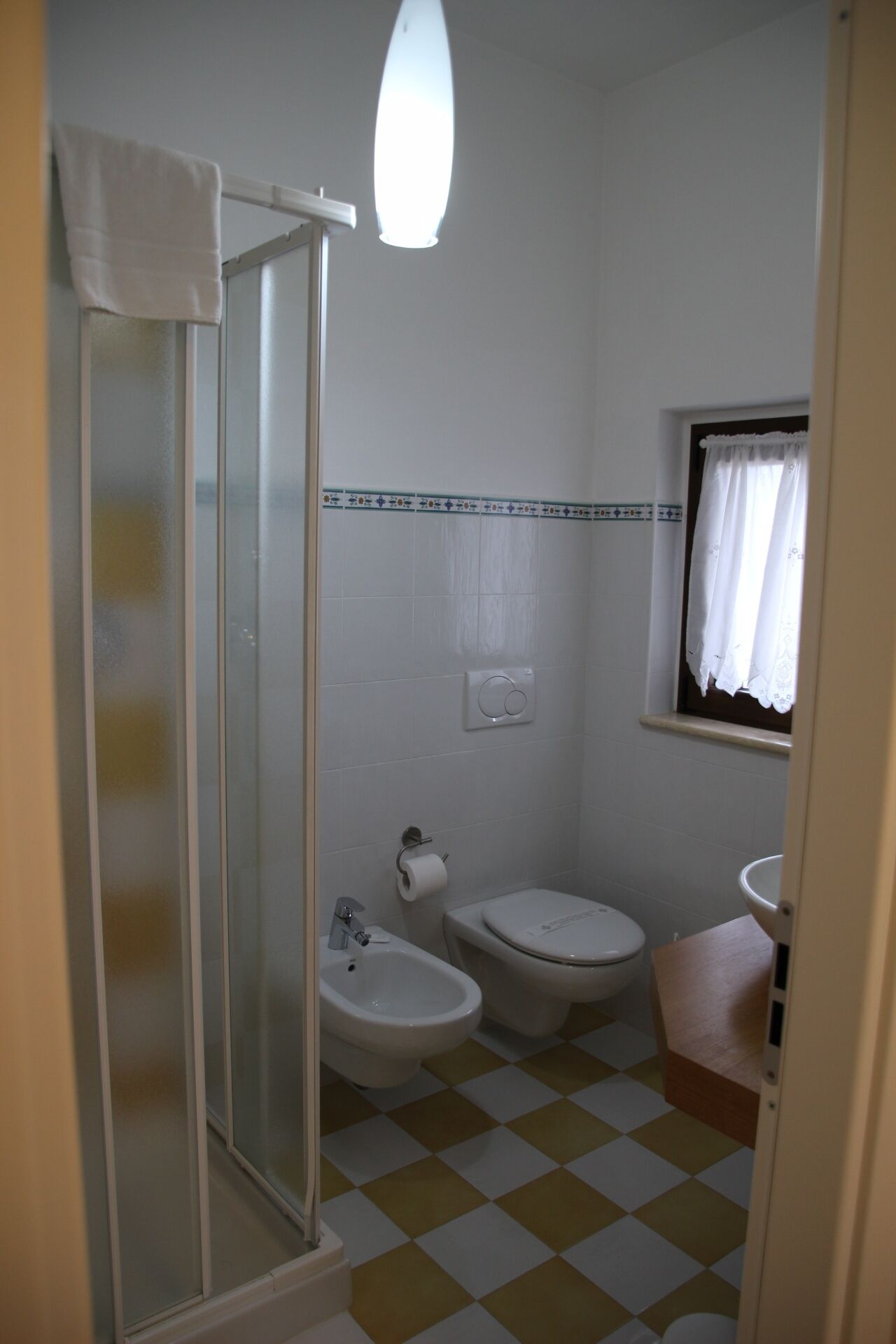A bathroom with a shower, toilet, bidet, and sink.