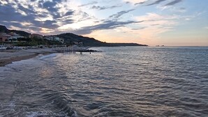 A coastal scene with a rocky shoreline, calm sea, and a distant shoreline with buildings. - Prati di Maja B&B (Miglianico)