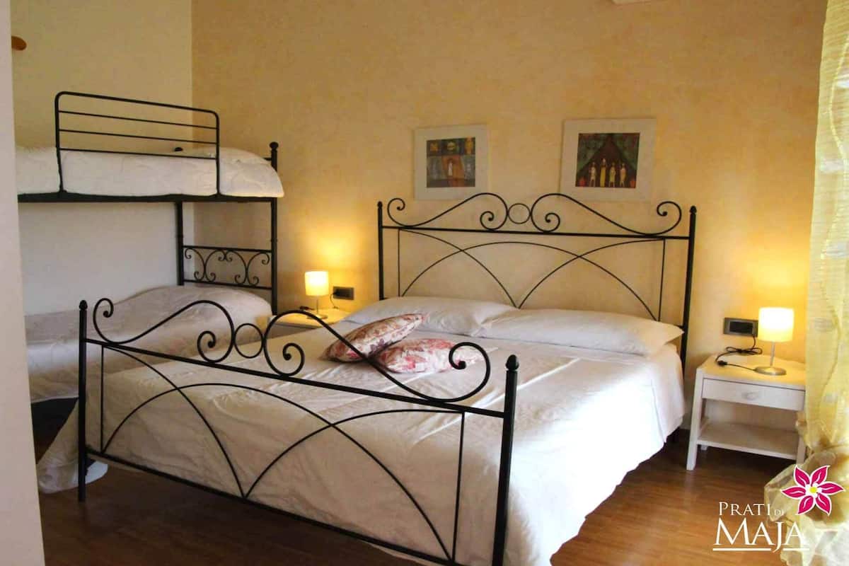 A room with a metal bed frame, two bedside tables with lamps, and two paintings on the wall.