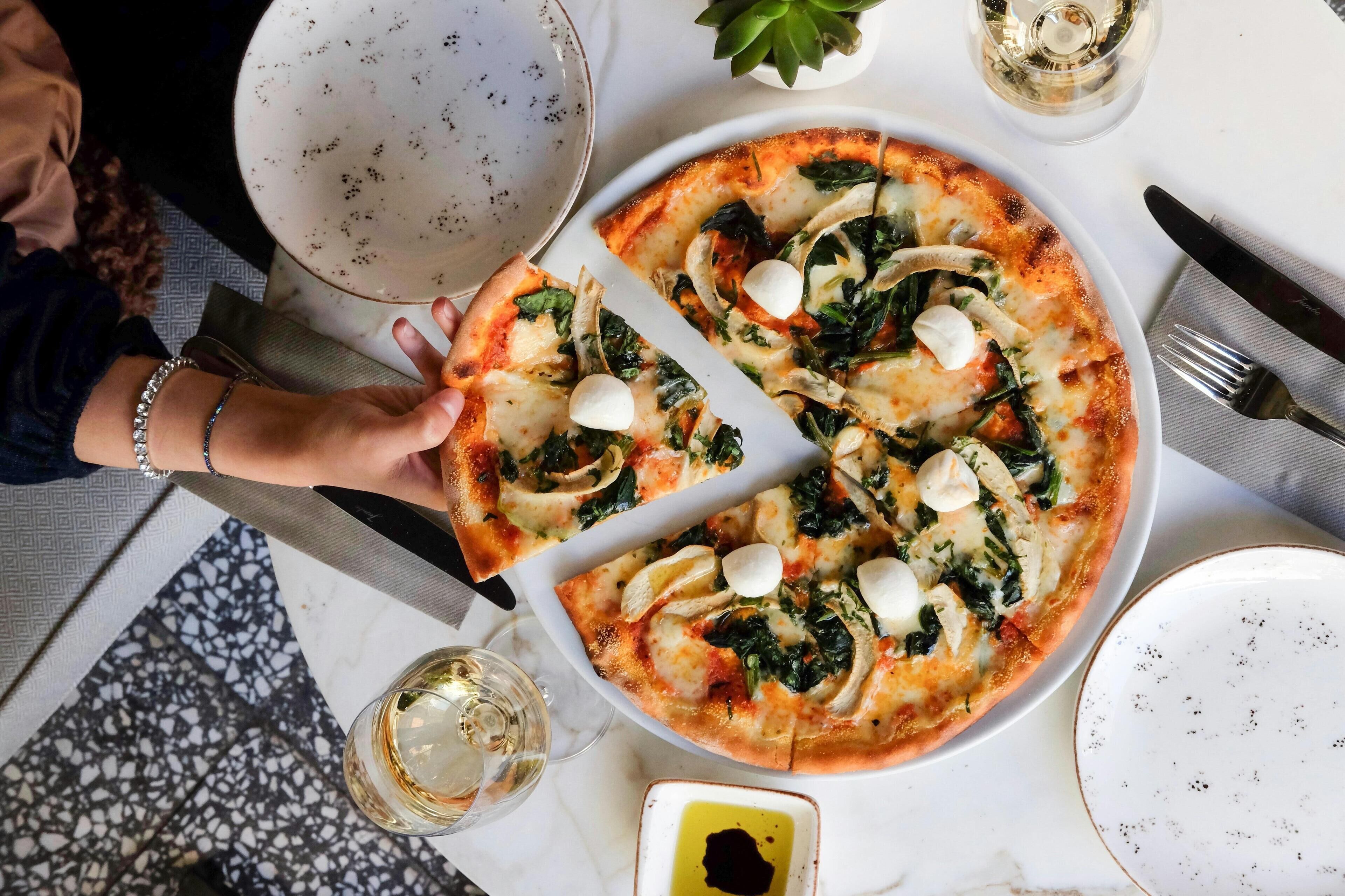 A pizza with spinach and mushrooms on a white plate.