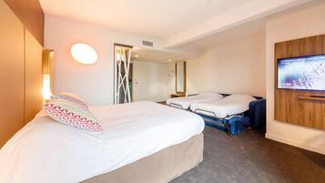 Et hotelværelse med en stor seng, en mindre seng, et fjernsyn på væggen og et spejl.
