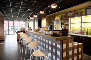 Zona de bar con un revoque de baldosas a cuadros, taburetes y una variedad de botellas y vasos en estantes.