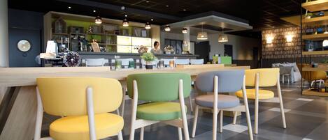 Een modern caféinterieur met een bar, zitplaatsen met houten poten en hanglampen.