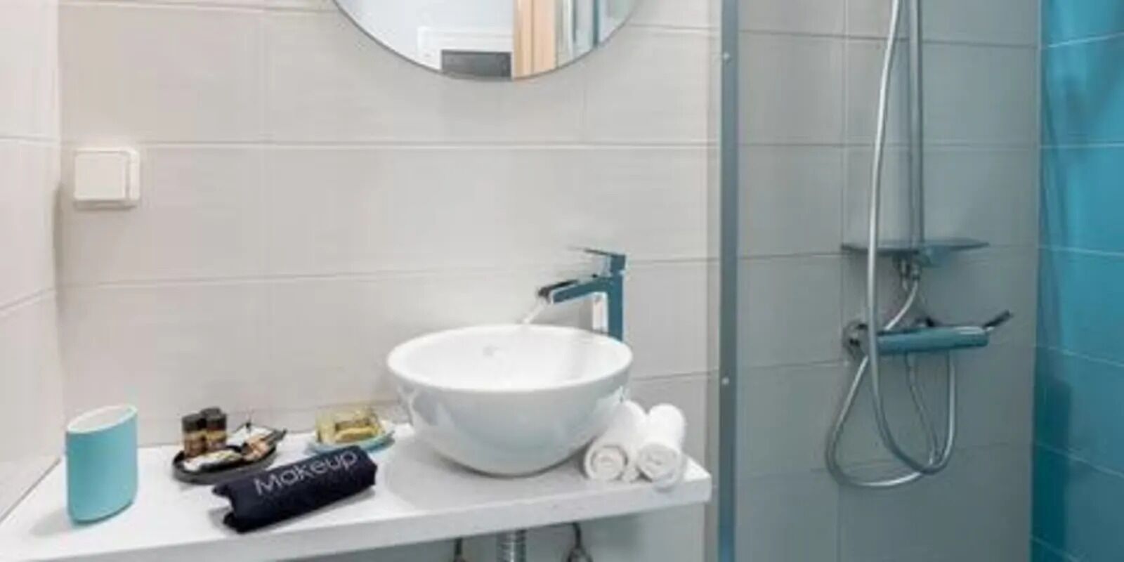 A bathroom with a white sink, a mirror, and a shower enclosure.