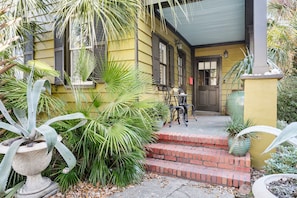 Step into a charming home with a welcoming porch, complete with a brick staircase and lush potted plants.