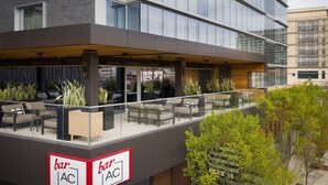 A modern building with a bar area featuring outdoor seating and a glass railing. - AC Hotel Austin-University (Austin)