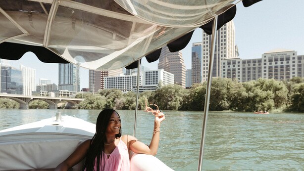 A person on a boat with a city skyline in the background. - AC Hotel Austin-University (Austin)
