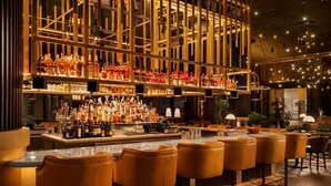 A bar area with multiple liquor bottles, a bar counter, and several bar stools. - AC Hotel Austin-University (Austin)