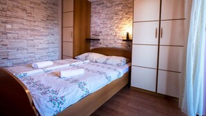 A bedroom with a wooden bed, a stone wall, and a wardrobe. - Apartment Sanic Rab 2 (Lopar)