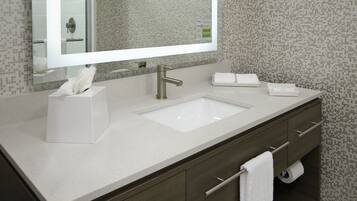 A modern bathroom with a large mirror, a sink, and a towel rack.