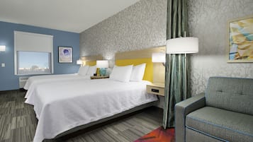 A hotel room with a large bed, two bedside tables, a chair, and a view of the city through the window.