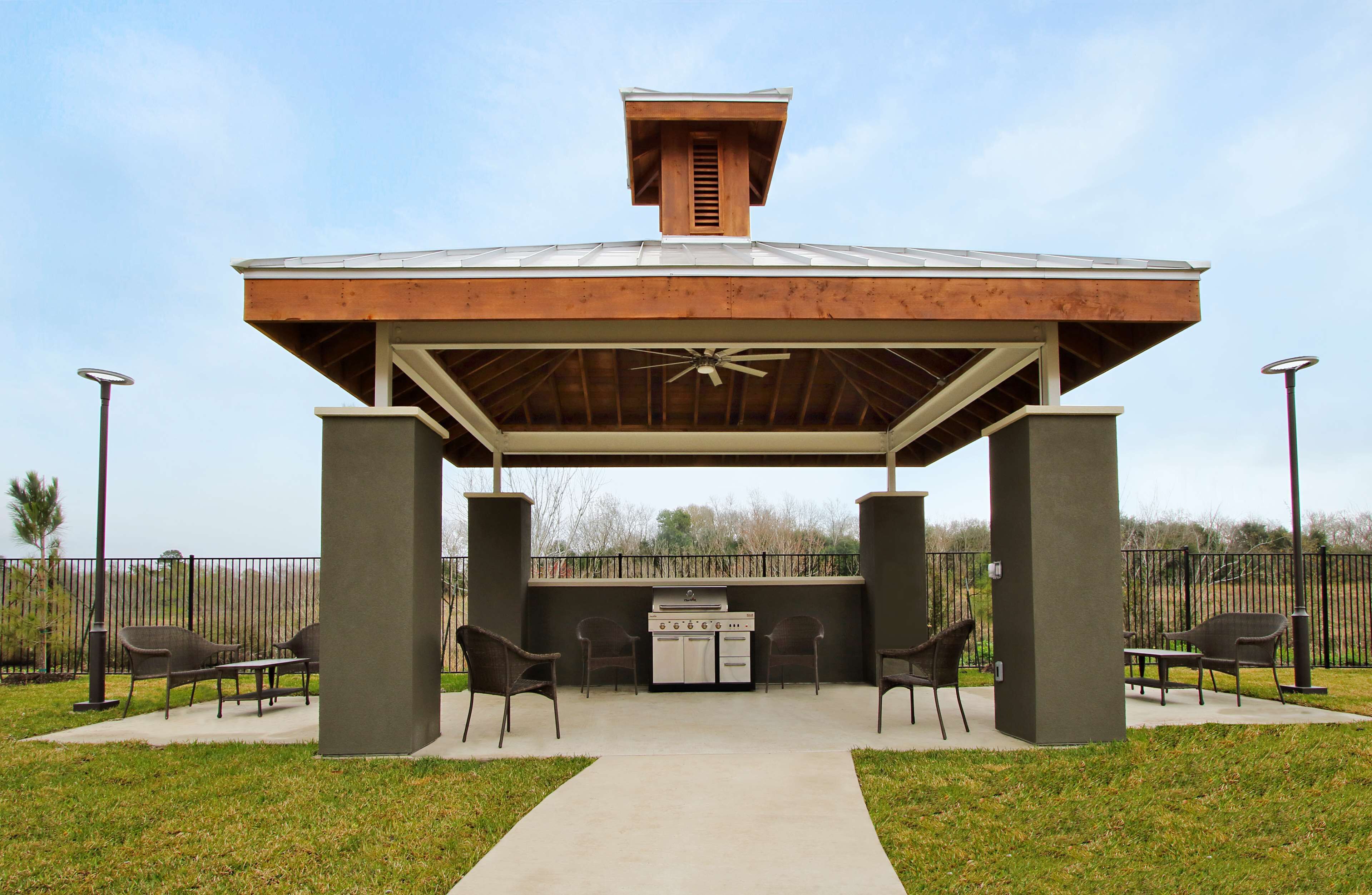 A covered outdoor patio with a grill and seating area.