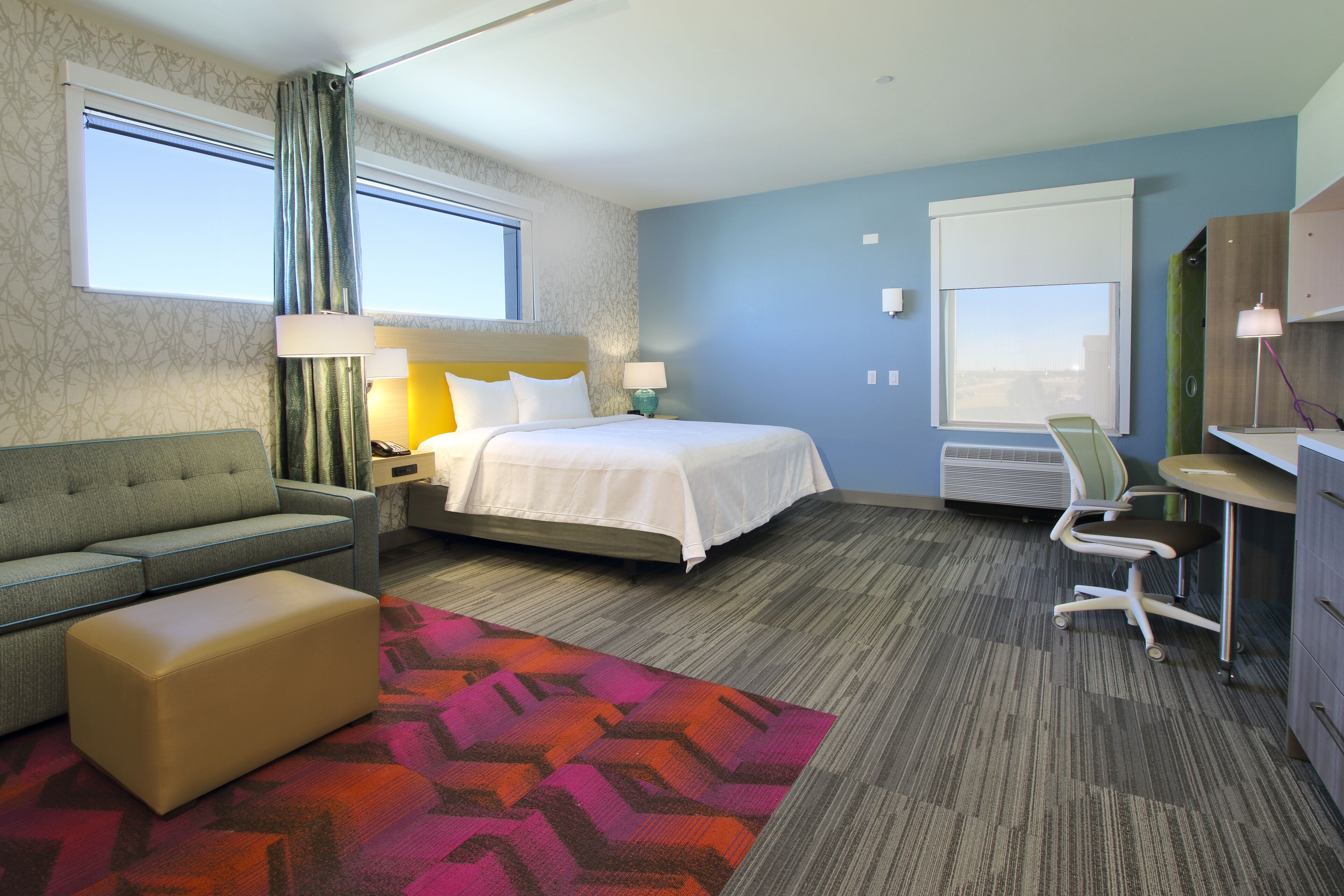 A hotel room with a bed, a sofa, a desk, and a chair.
