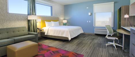 A hotel room with a bed, a sofa, a desk, and a chair.