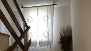 A staircase with wooden handrails leading to a landing. A decorative curtain with a geometric pattern hangs at the top of the landing. - Apartments Tarcizio (Cres)