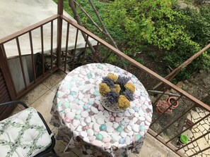A round table covered with pebbles and a decorative centerpiece, surrounded by a metal railing and potted plants. - Apartments Tarcizio (Cres)