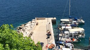 A harbor with boats docked, a concrete quay, and rocky terrain. - Apartments Tarcizio (Cres)
