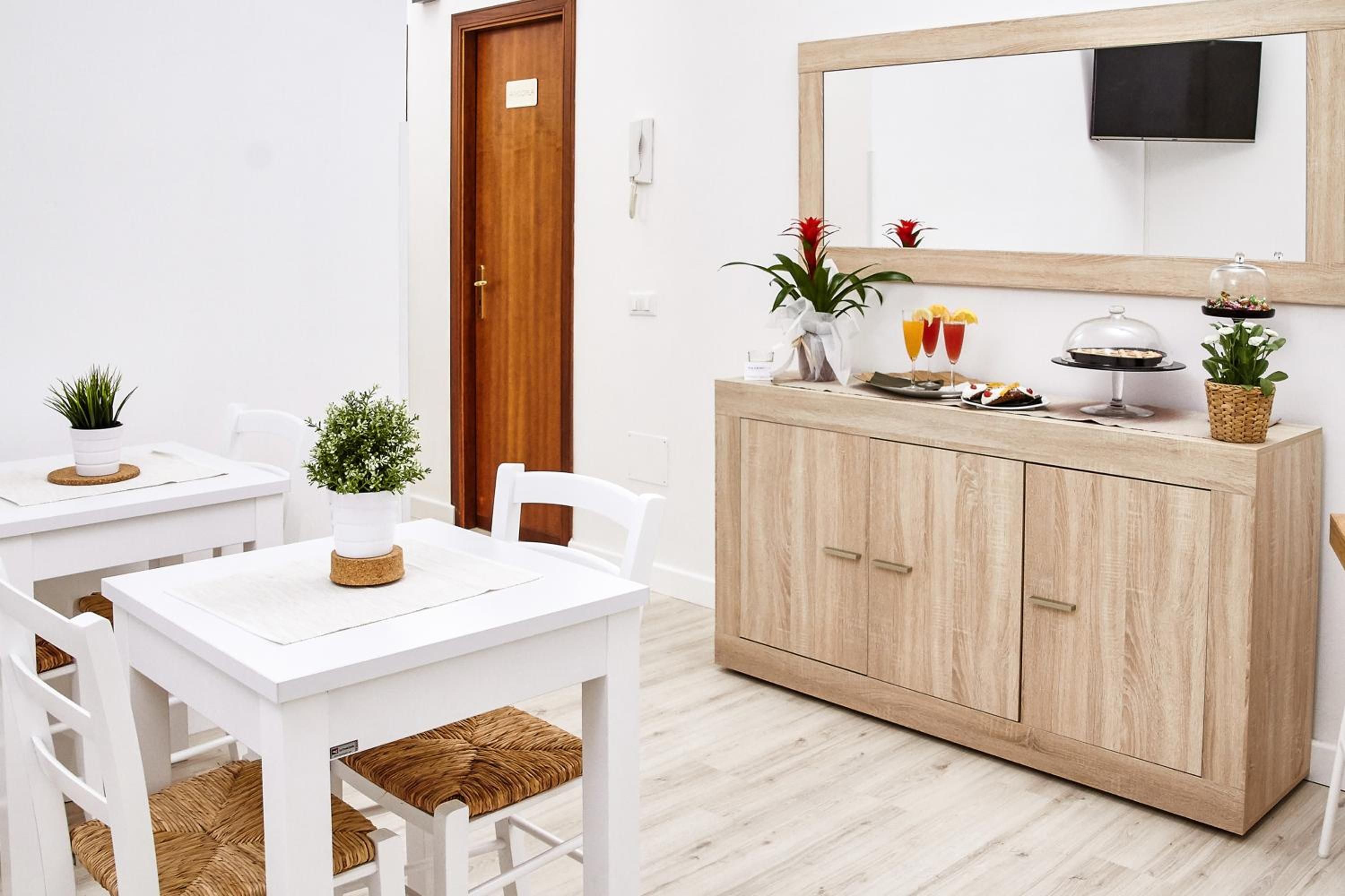 Ein modernes, minimalistisches Zimmer mit weißen Möbeln, einem Holzschrank und einem Spiegel.