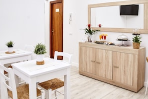 A modern, minimalist room with white furniture, a wooden cabinet, and a mirror. - Palermo Inn (Palermo)