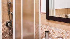 Une salle de bain avec une douche, un lavabo et un miroir.