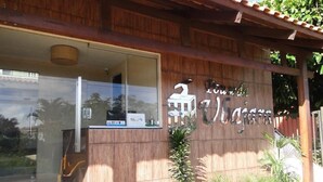 A building with a wooden facade, a large glass entrance, and a sign with the name "Hotel de la Costa". - Pousada Ubajara (Ubajara)