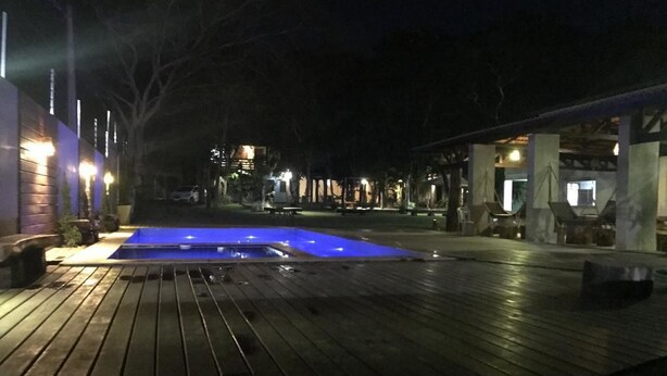 A wooden deck with a swimming pool, surrounded by buildings and trees. - Pousada Ubajara (Ubajara)