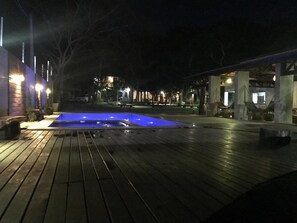 A wooden deck with a swimming pool, surrounded by buildings and trees. - Pousada Ubajara (Ubajara)
