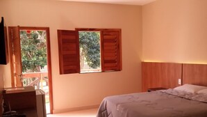A bedroom with a bed, a desk, and two windows with wooden shutters. - Pousada Ubajara (Ubajara)