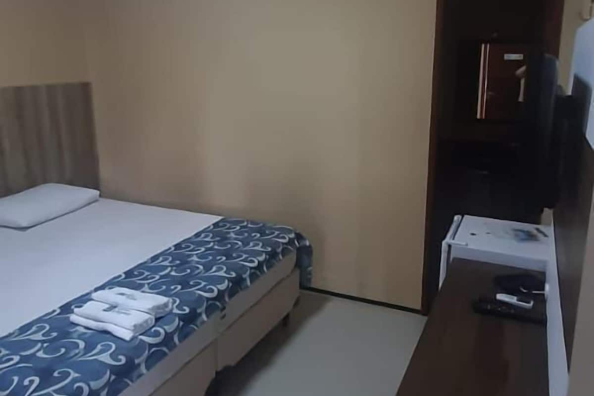 A hotel room with a bed, a desk, and a television.