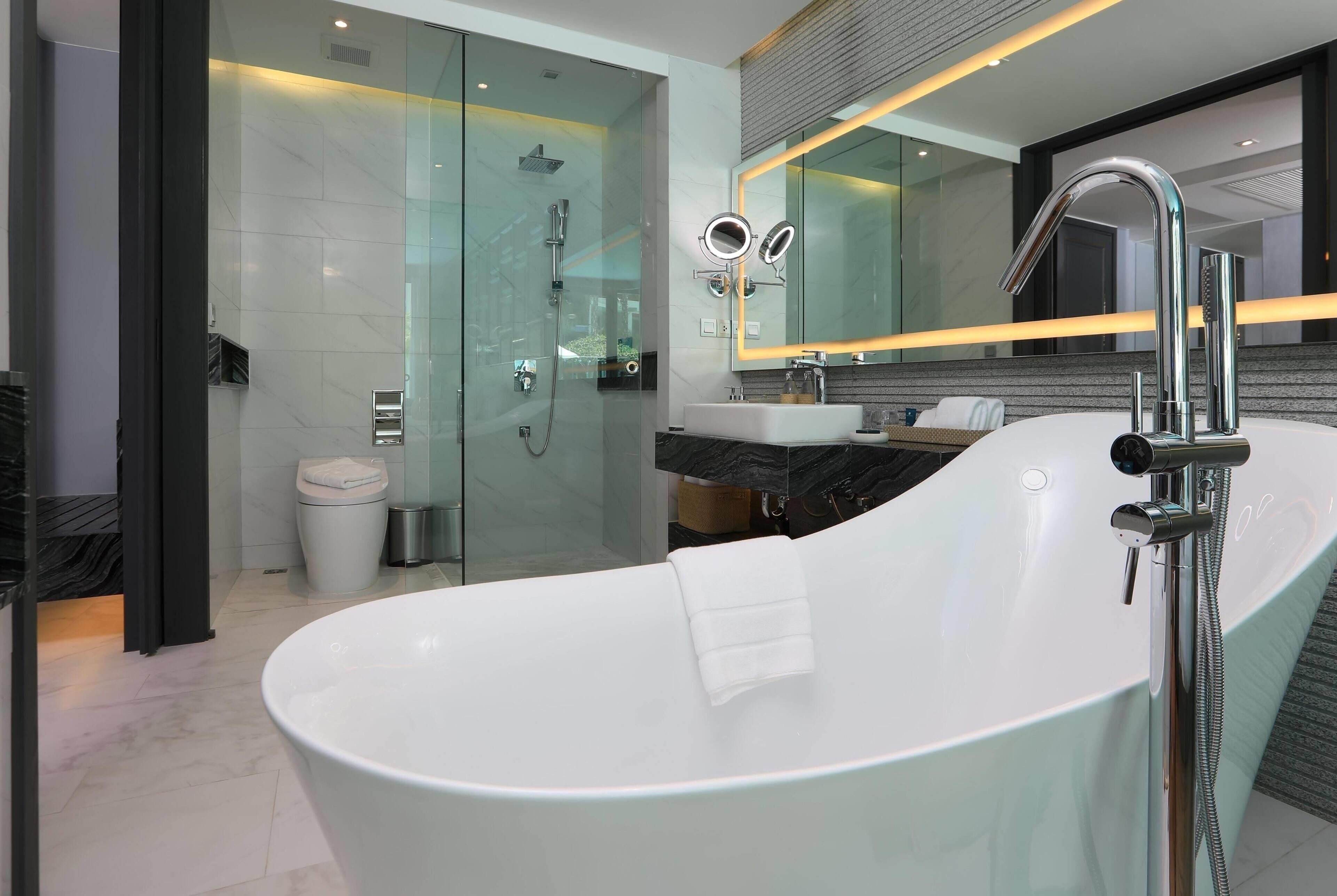 Un baño moderno con una bañera independiente, una ducha con cerramiento de vidrio y un tocador con espejo.