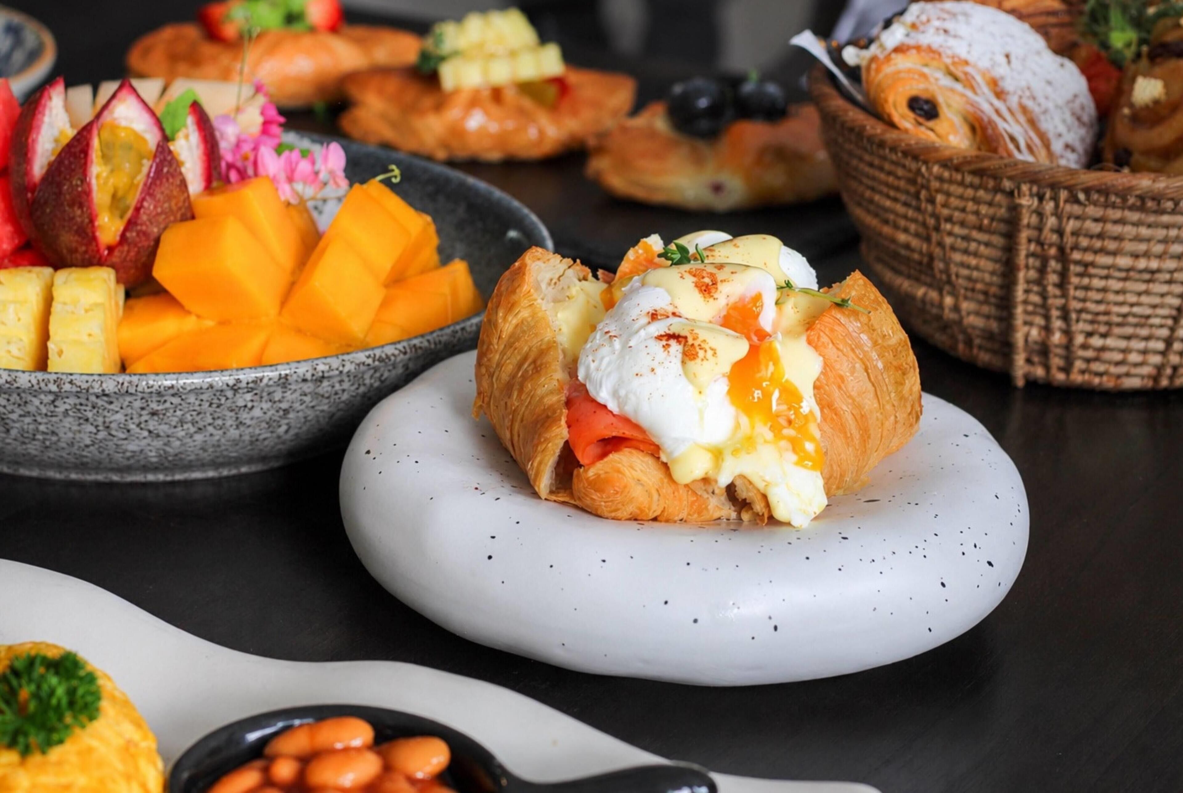 A breakfast spread with pastries, fruits, and a bowl of beans.