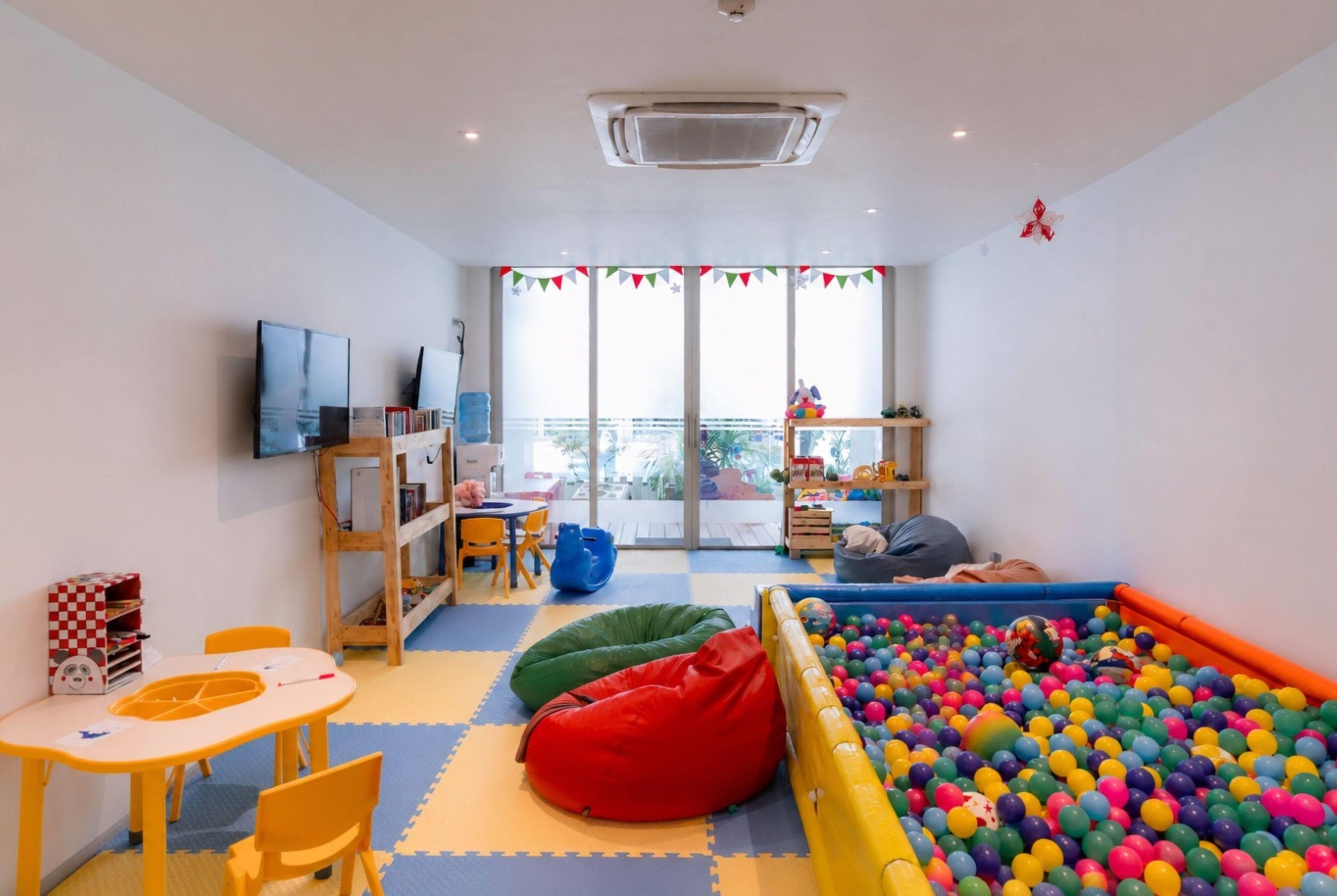 A children's playroom with a ball pit, seating areas, and a television.