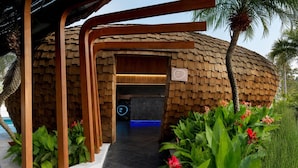 A modern building with a curved wooden exterior, a digital display, and lush greenery. - Wyndham Grand Nai Harn Beach Phuket (Rawai)