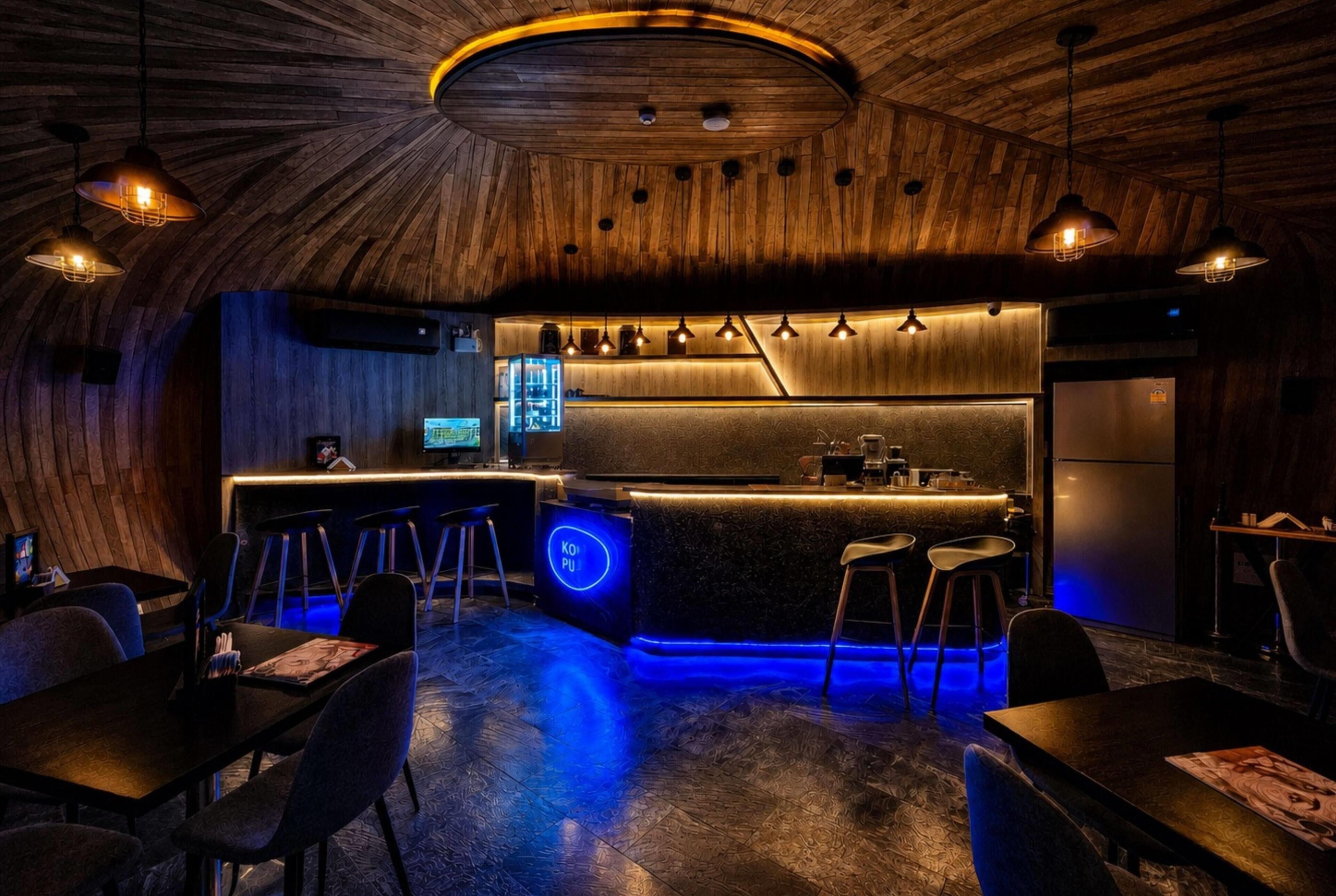 A modern bar area with a wooden ceiling, bar stools, and a neon-lit counter.