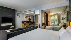 A modern hotel room with a large bed, a flat-screen TV, a desk with a chair, a bathroom with a bathtub, and a large window. - Wyndham Grand Nai Harn Beach Phuket (Rawai)