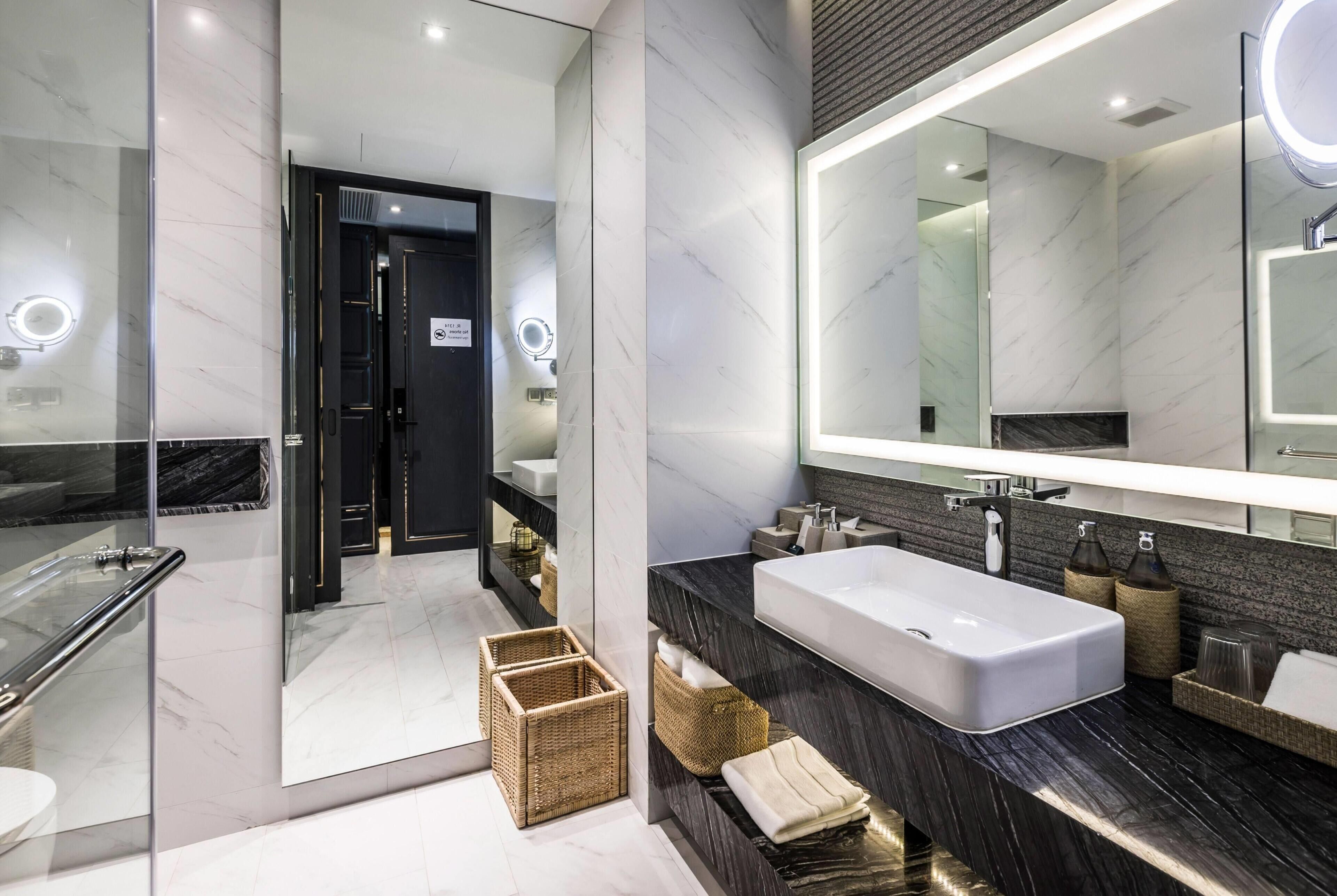 Un baño moderno con un espejo grande, un lavamanos rectangular y una cabina de ducha de vidrio.