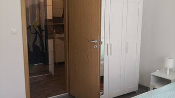 Quarto com cama, guarda-roupa e banheiro visível por uma porta aberta.