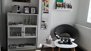 A modern room with a white bookshelf, a black chair, a small table, and a radiator. - Green Garden Plus Apartman (Budapest)