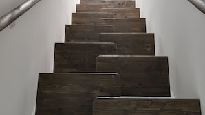 A staircase with wooden steps and metal handrails, leading to a bright room at the top. - Green Garden Plus Apartman (Budapest)
