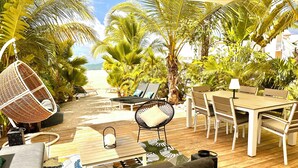 Eine Holzterrasse mit Gartenmöbeln, darunter eine Sitzecke mit Sofa, Stühlen und einem Tisch.