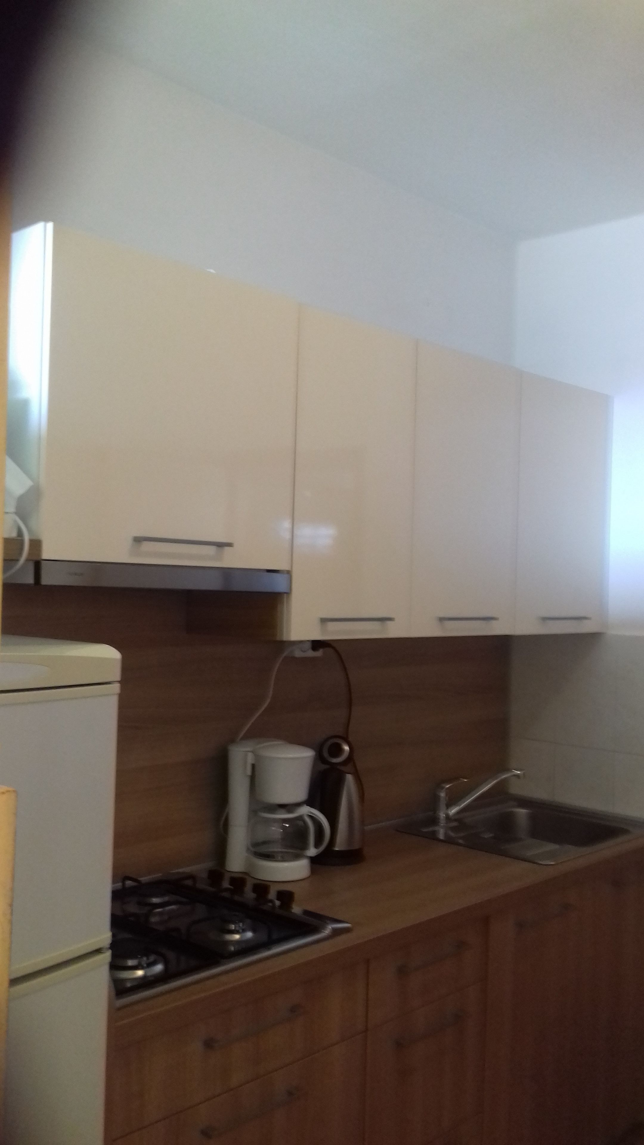 A compact kitchen with wooden cabinets, a gas stove, a coffee maker, and a sink.