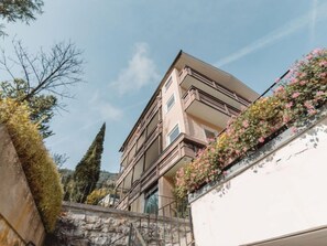 Un immeuble à plusieurs étages doté de balcons, d’un mur en pierre et surplombant un ciel dégagé.