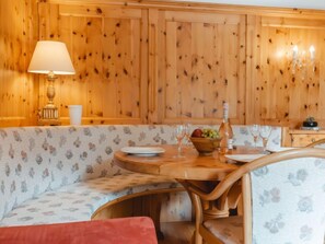 Un intérieur chaleureux en bois, avec une table ronde en bois, un canapé à motifs floraux et une lampe.