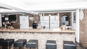 Zona de bar con pared de ladrillo, taburetes de madera y una encimera blanca.
