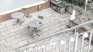 Un patio al aire libre con paredes de ladrillo, piso de losas de piedra y una parrilla de barbacoa.