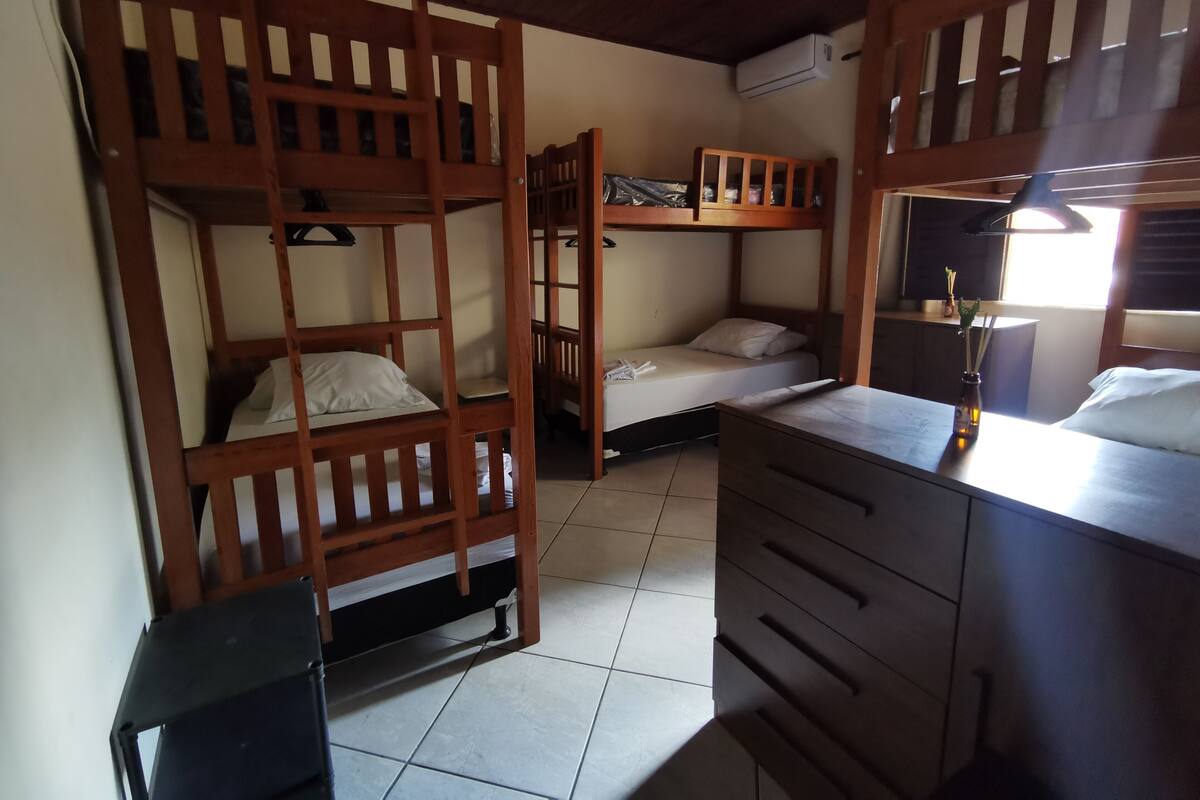 Una habitación con literas, un escritorio, un aparador y un aire acondicionado.
