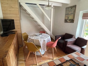 A dining area with a table, chairs, a television, and a staircase.